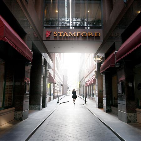 Stamford Plaza Melbourne Hotel Exterior foto The photo depicts a narrow alley or passageway, possibly in an urban setting. On one side, there are storefronts with canopies, and on the opposite side, there is a prominent sign reading "STAMFORD." The pathway is lined with buildings, creating a se
