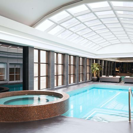 Stamford Plaza Melbourne Hotel Exterior foto The photo shows an indoor swimming pool area. The pool is rectangular and has clear blue water, surrounded by a sleek, modern design. On one side, there is a round hot tub made of dark stone. Large windows line the walls, allowing natural light to fi