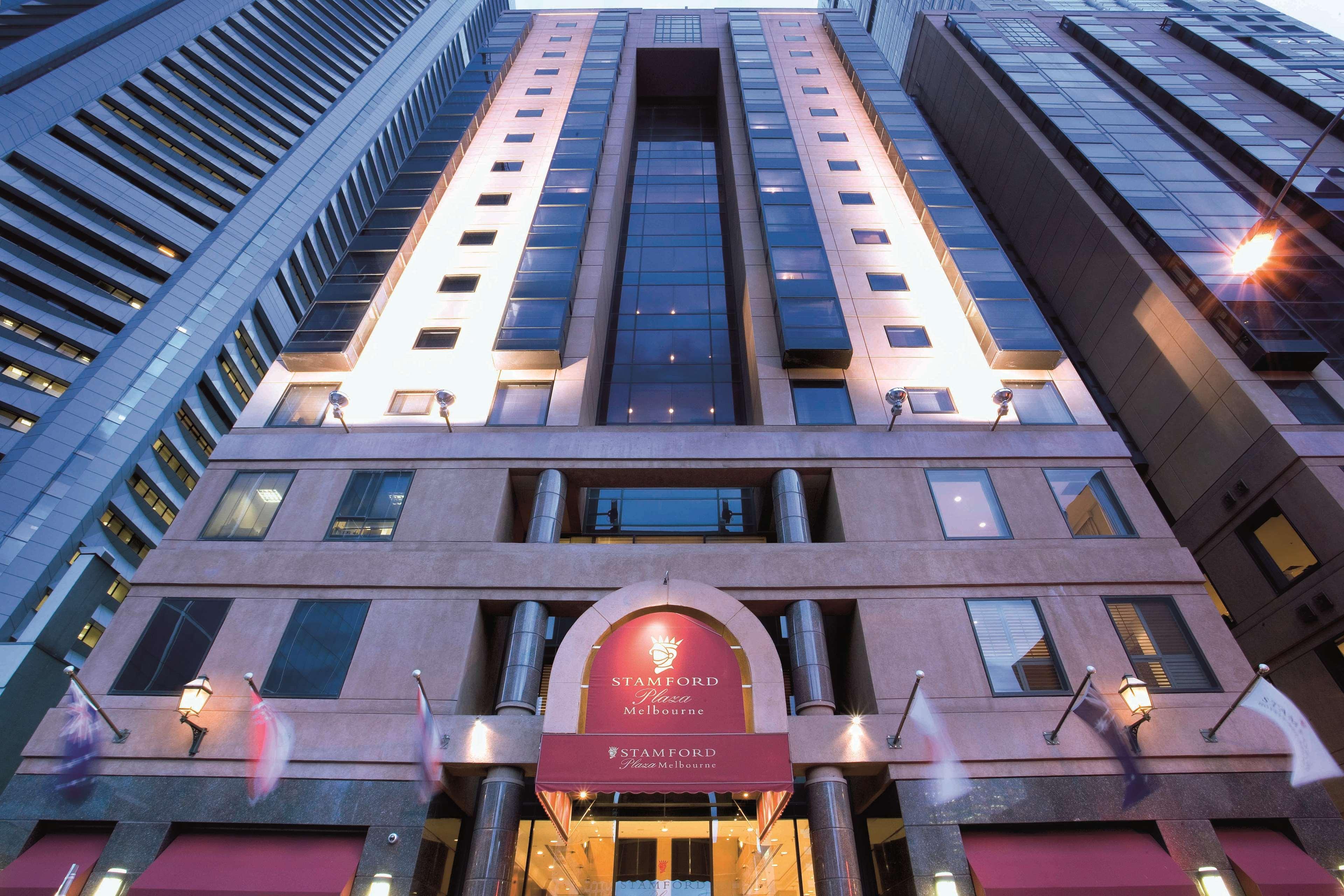 Stamford Plaza Melbourne Hotel Exterior foto The photo shows the exterior of a modern hotel building. The structure appears tall and features a combination of glass and stone elements. Large windows are prominent, particularly in the center section, which suggests a contemporary architectural s