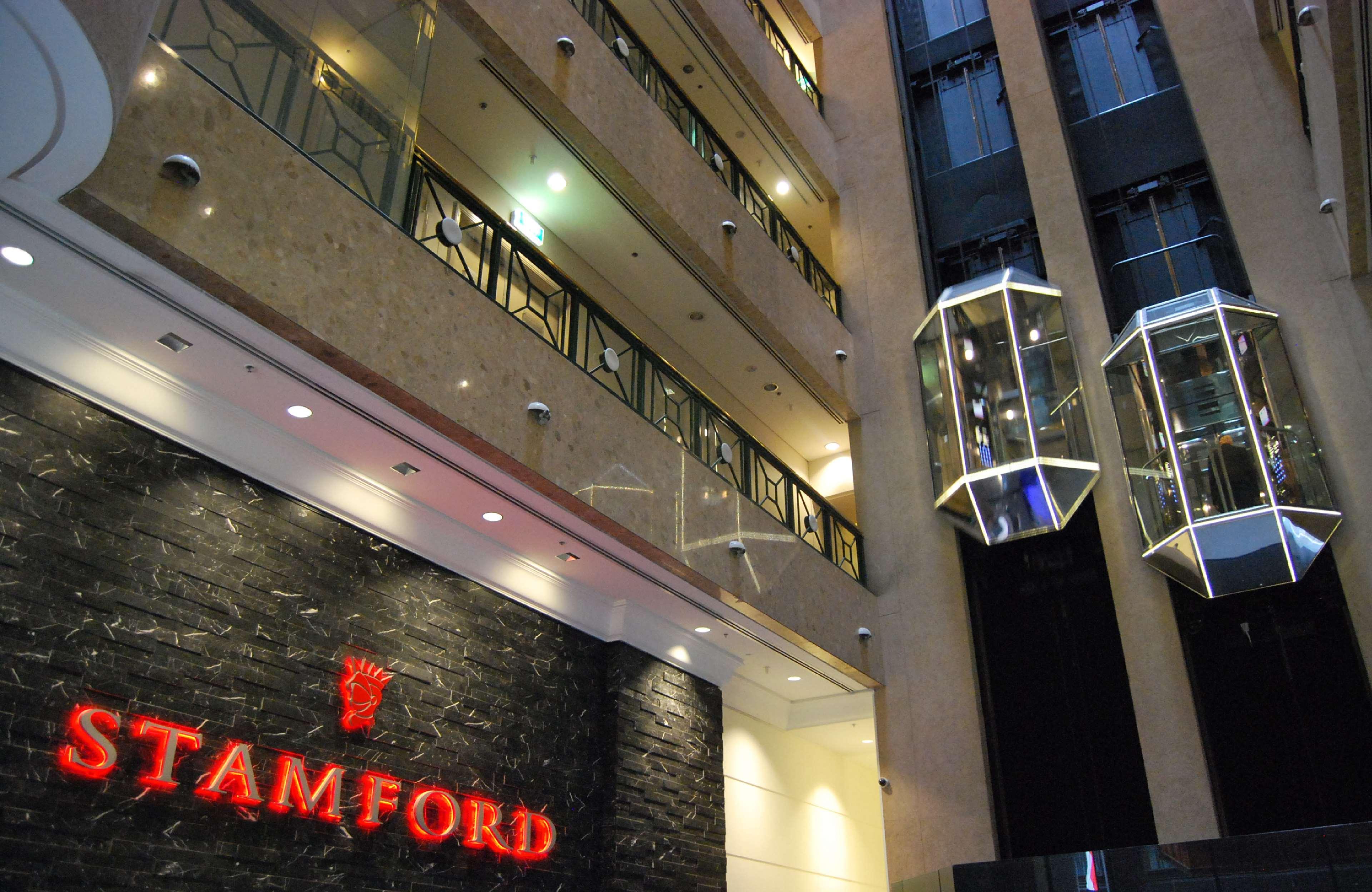 Stamford Plaza Melbourne Hotel Exterior foto The photo shows the interior of a building, likely a hotel or commercial space. There is a prominent sign with the name "STAMFORD" in red lettering against a dark stone background. The building features several floors, visible from the photograph, wi