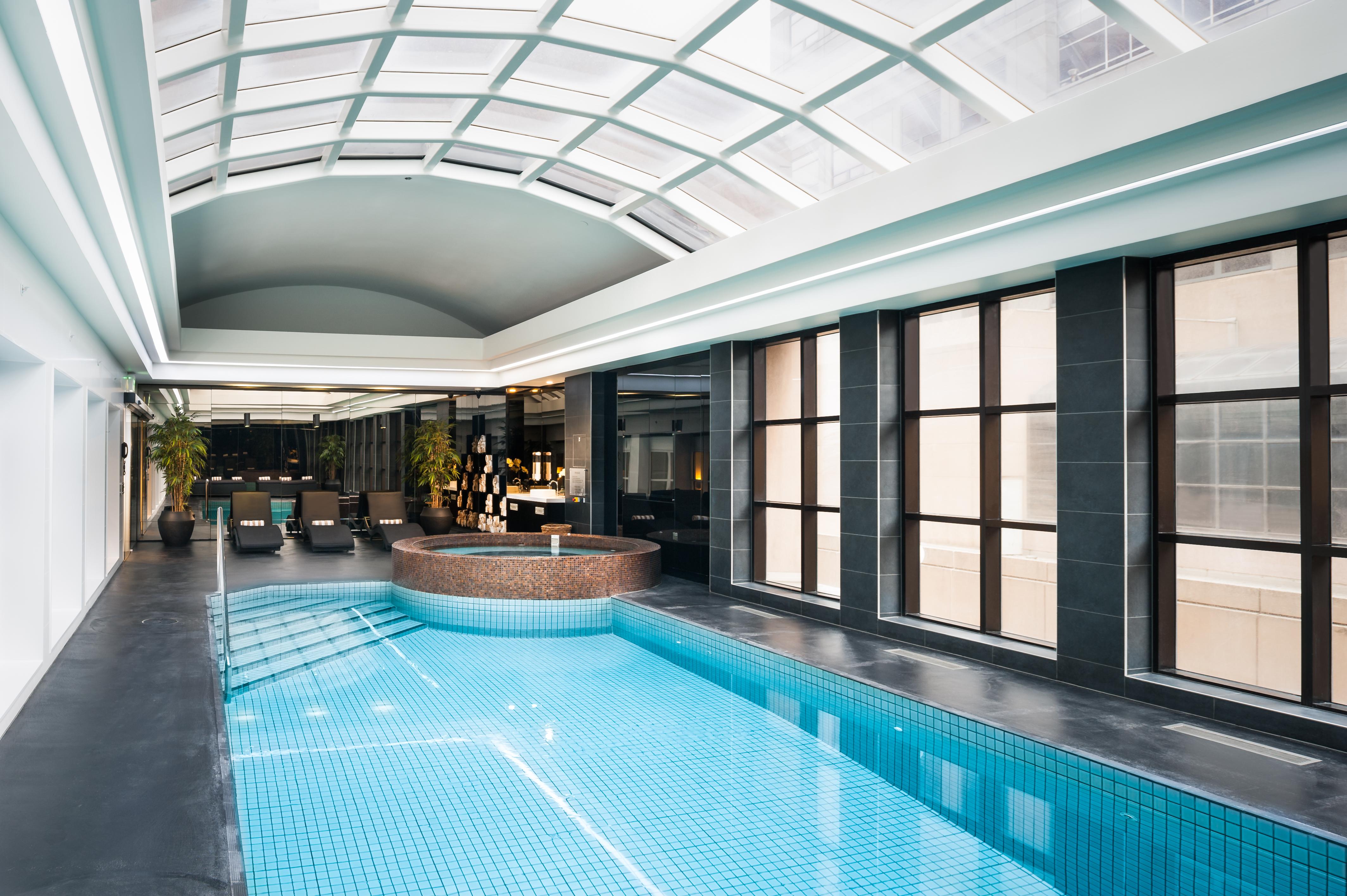 Stamford Plaza Melbourne Hotel Exterior foto The photo shows an indoor swimming pool area with a modern and sleek design. The pool is rectangular and features bright blue tiles. Above the pool, there's a large, transparent glass ceiling that allows natural light to flood the space. Surrounding 