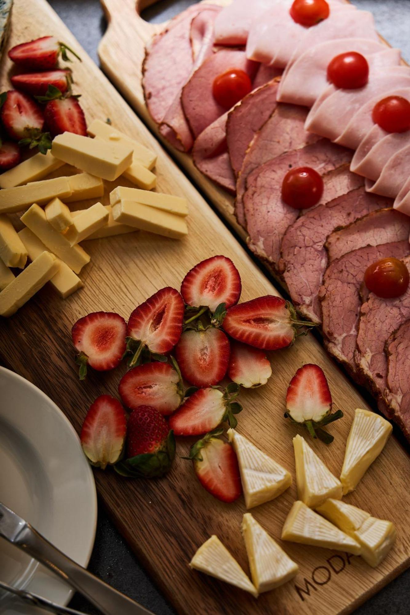 Stamford Plaza Melbourne Hotel Exterior foto The photo displays an assortment of food items arranged on a wooden surface. There are slices of various meats, including ham, alongside round cherry tomatoes. Next to the meat, there are several pieces of yellow cheese cut into sticks. Additionally,