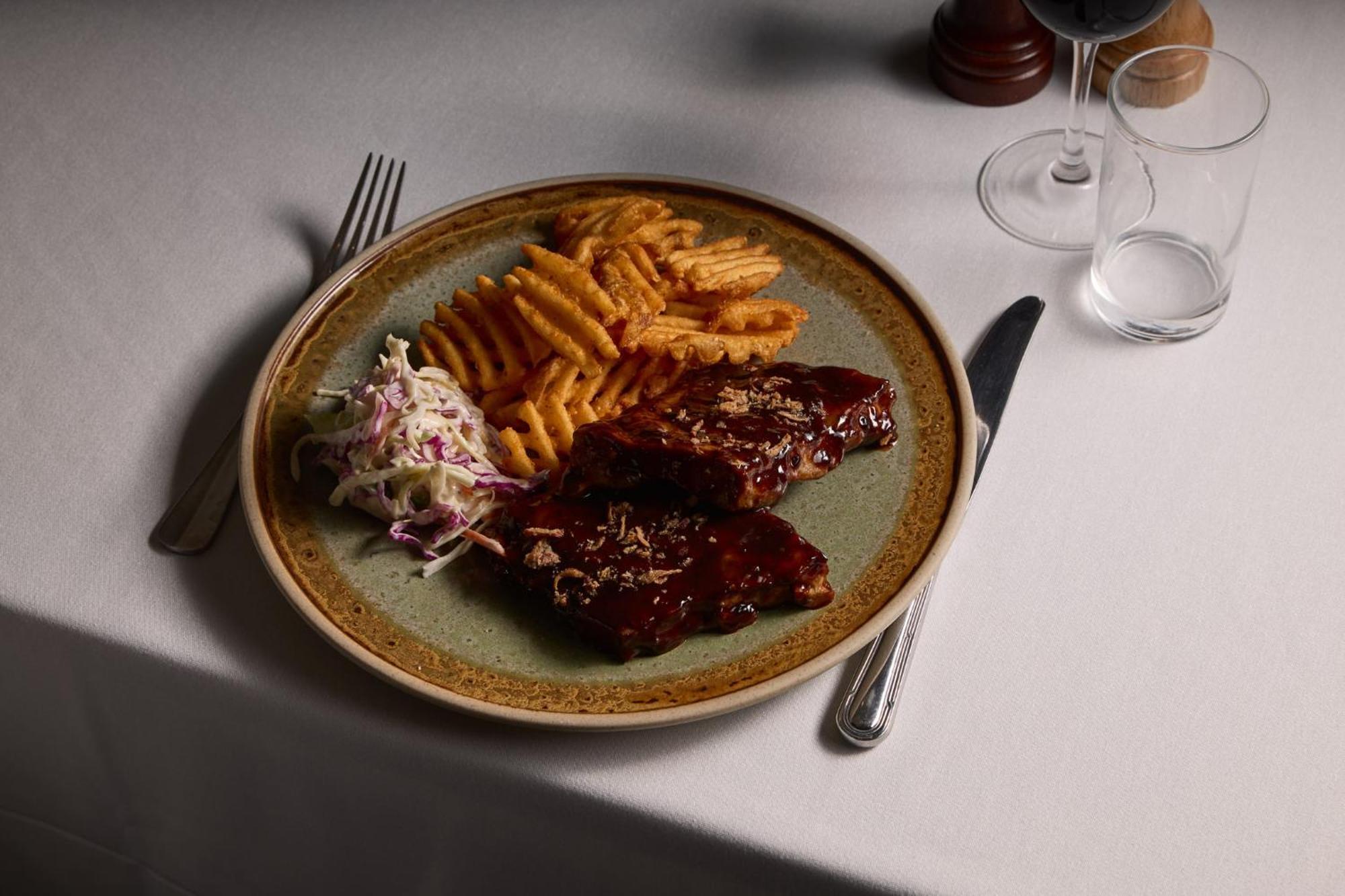 Stamford Plaza Melbourne Hotel Exterior foto The photo displays a plate of food featuring two pieces of steak that appear to be glazed with a rich sauce. Alongside the steak, there are crinkle-cut fries arranged neatly on one side of the plate. Additionally, there's a small serving of coleslaw,