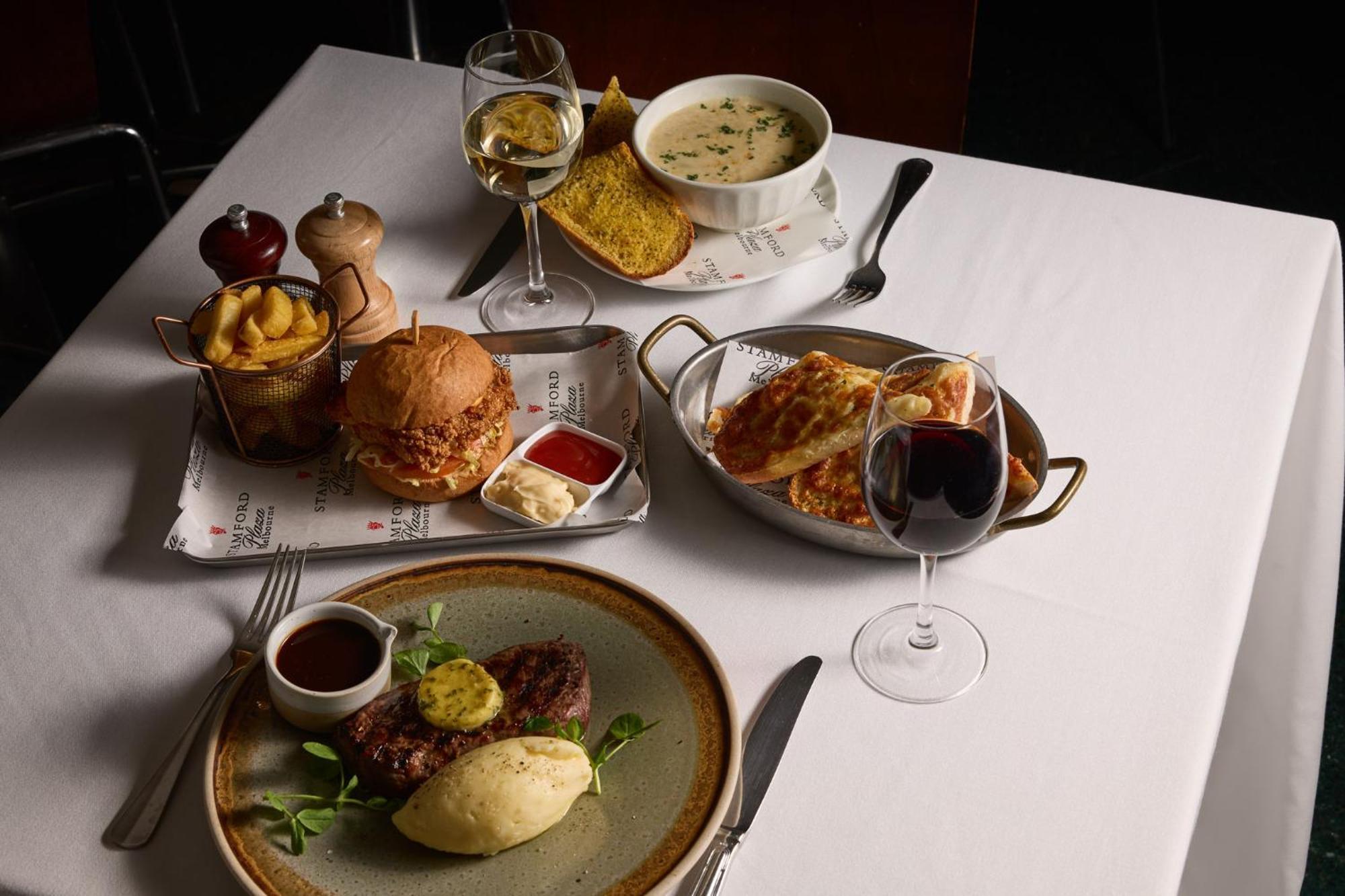 Stamford Plaza Melbourne Hotel Exterior foto The photo showcases a variety of food and drinks arranged on a table set with a white tablecloth. 

1. **Main Dish:** A plate features a portion of steak topped with a slice of butter, accompanied by mashed potatoes and a garnish of greenery.
2. **Bu