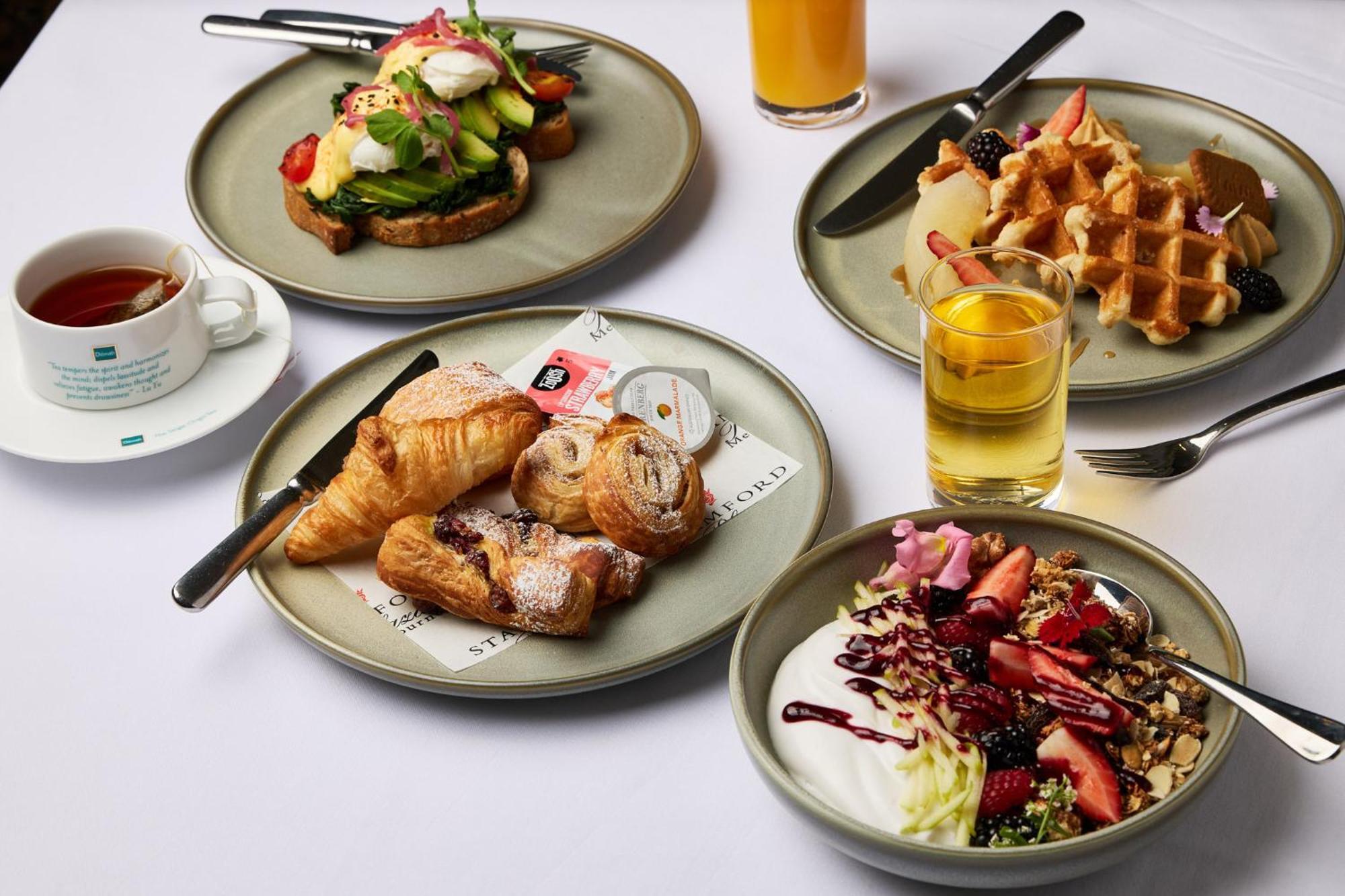 Stamford Plaza Melbourne Hotel Exterior foto The photo displays a variety of breakfast items arranged on several plates. 

1. **Top-left Plate**: Features an open-faced sandwich with avocado, topped with poached eggs and garnished with vegetables.
2. **Top-right Plate**: Contains freshly made w